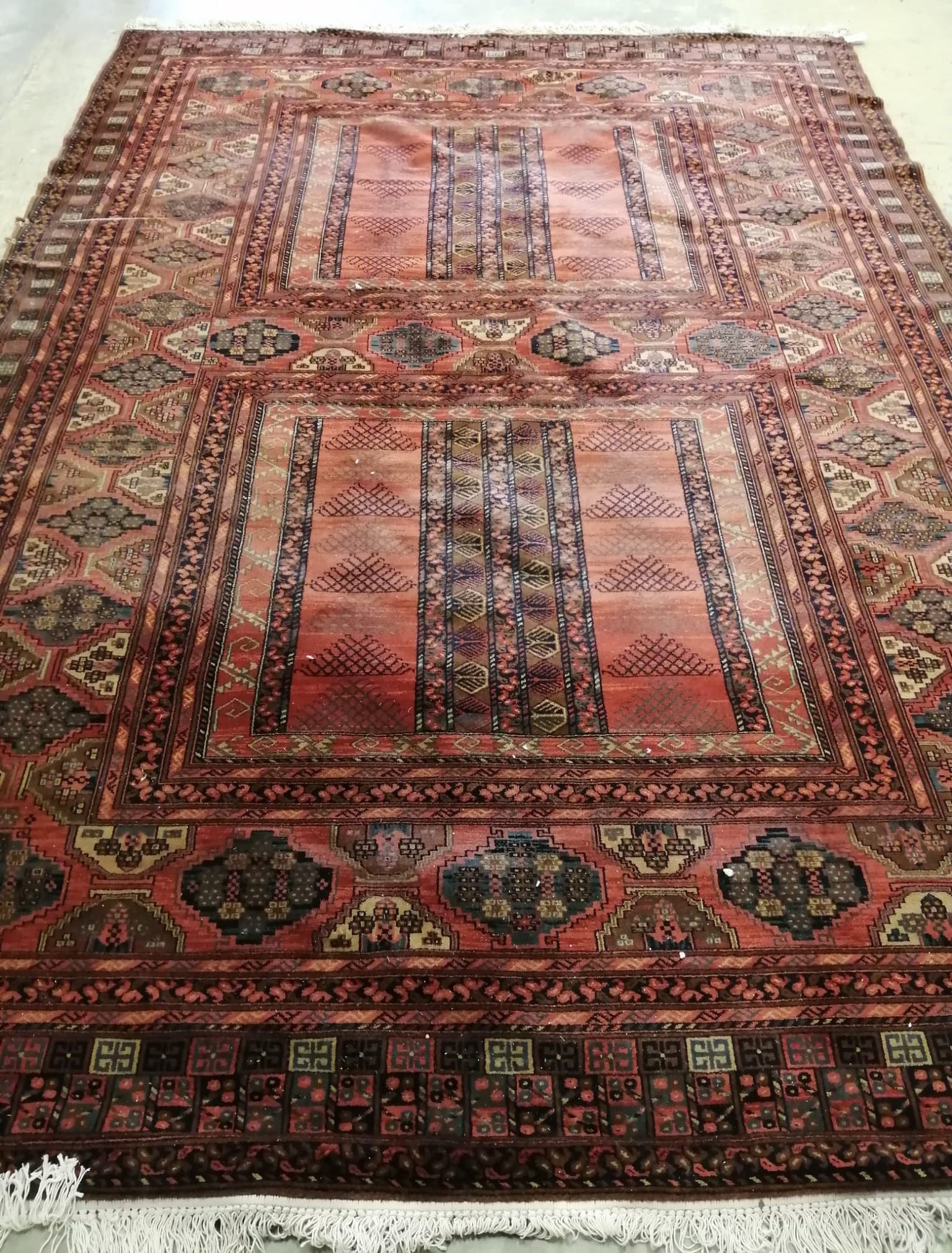 An Afghan style red ground carpet, 350 x 250cm